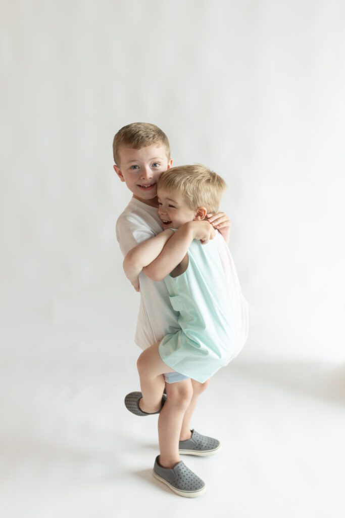 Two siblings hugging one another in a  indoor studio in Columbia, South Carolina